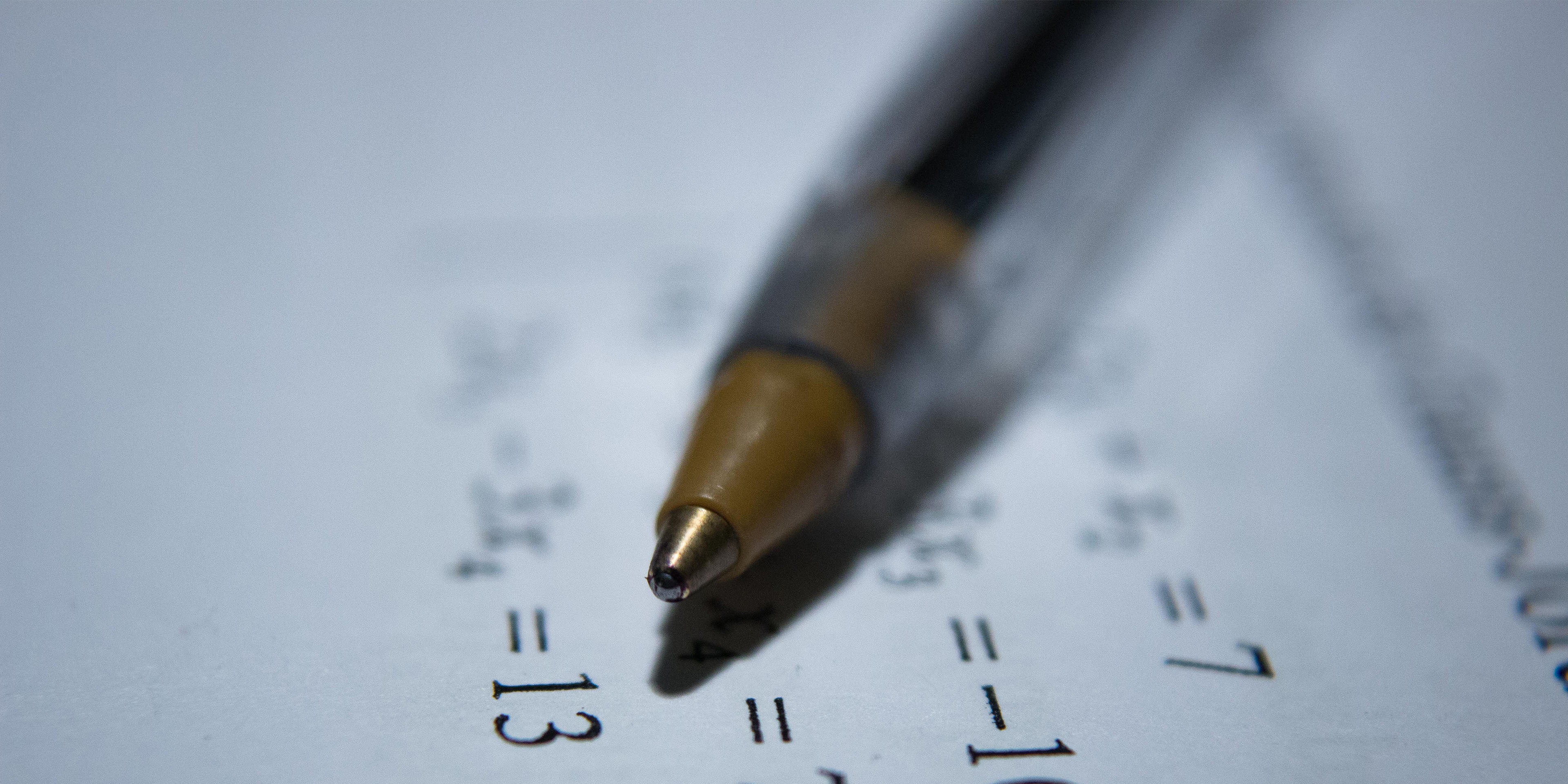 Pen lying on paper with mathematical equations printed on the paper.