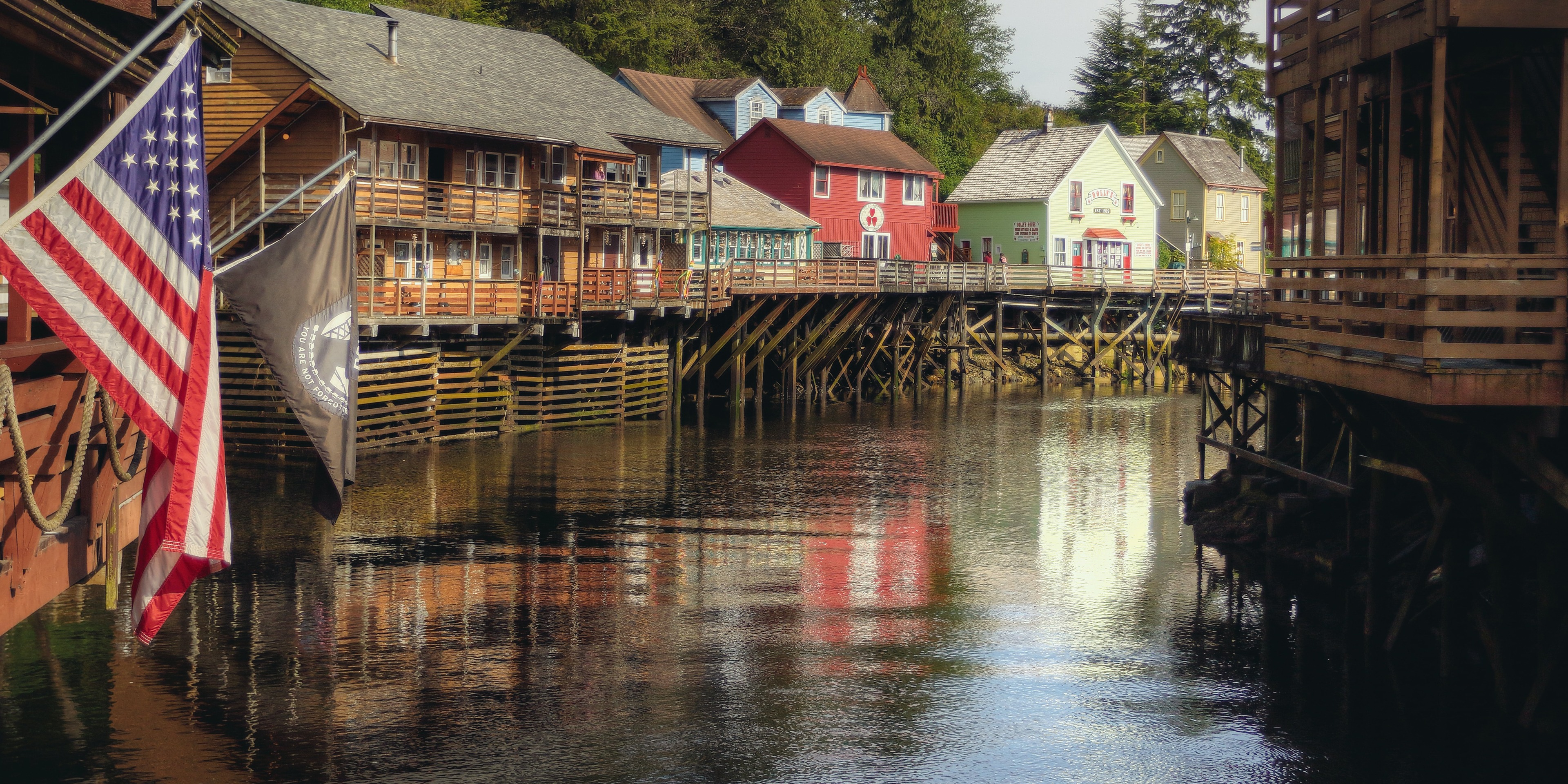 A row of houses and buildings along a riverbank sitting on piles in the water.