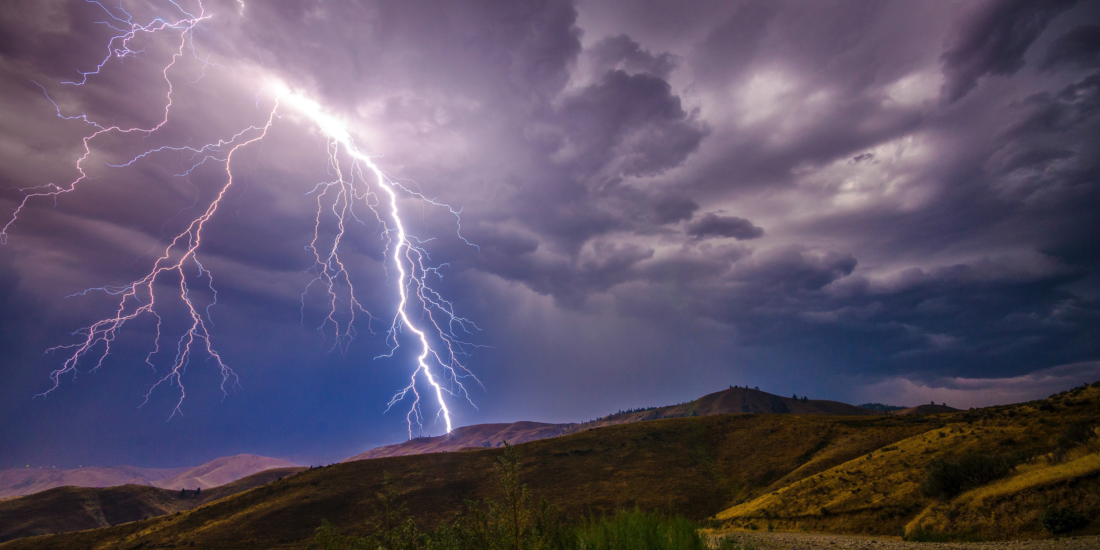 Lightning across the sky above mountains.